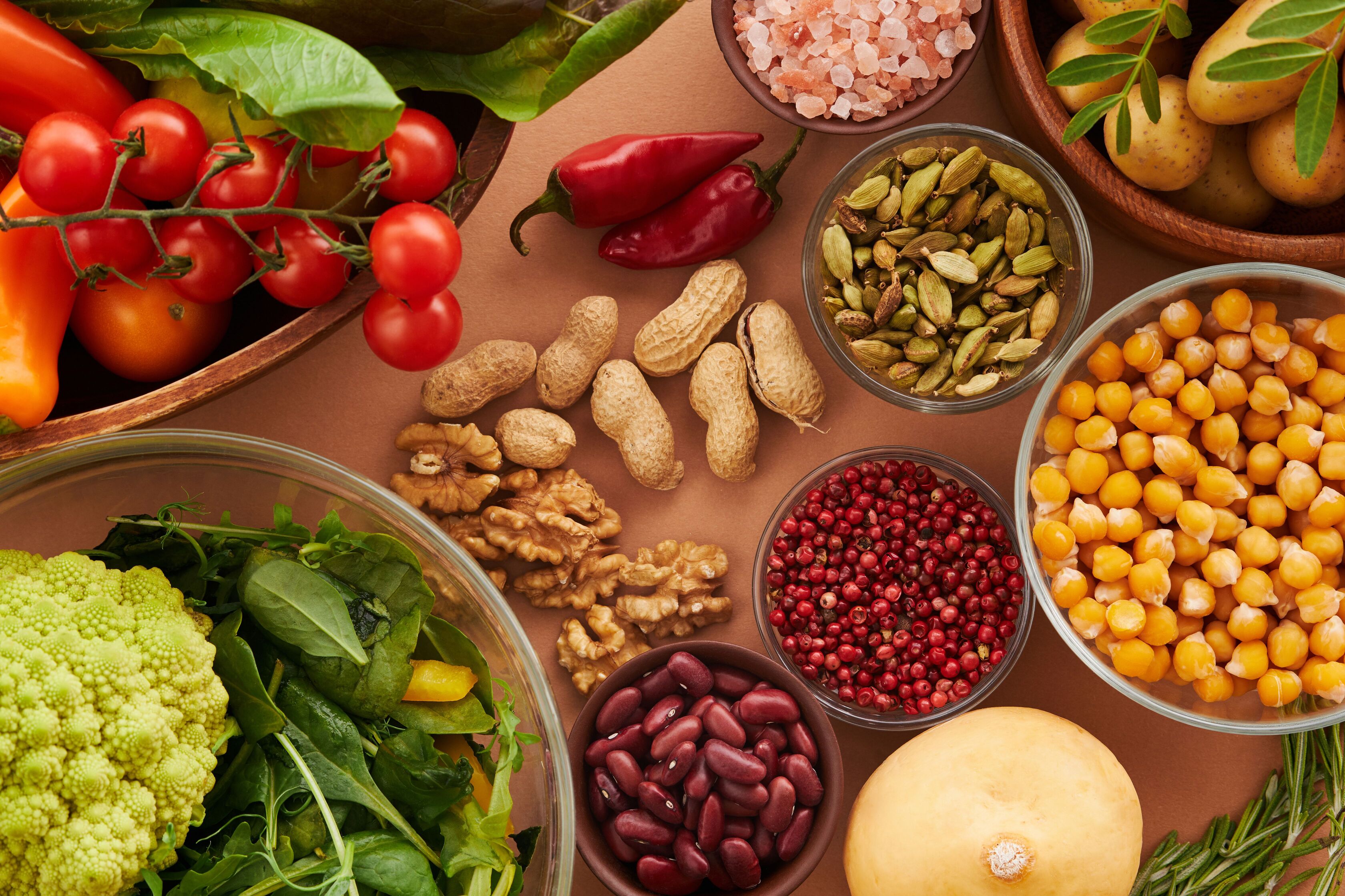 Table full of fresh vegetables, tomatoes, nuts, chickpeas, beans and spices in bowls